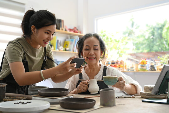 Happy young woman and middle aged woman creating handicraft crockery in workshop. Activity, handicraft, hobbies concept