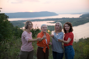 multi generation a group of women friends with sparklers has fun spending time together in nature on a summer evening