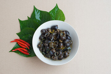Bowl of Thai traditional food, curry freshwater snails with green leaves and red chilies. Concept :  Thai local food in northern of Thailand. Cooking and eating cuisine.                     