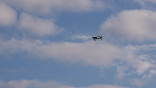 Fly small civil aircraft in sky. Double seat plane flies forward in cloudy sky. agricultural air vehicle carrying employee or business owner flies to work.