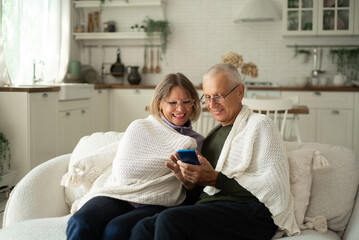 A couple of pensioners are warming up and sharing news at home on the couch.