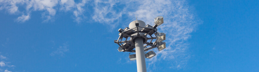 Panorama close up view of high mast lighting pole lights tower with antenna under cloud blue sky in...