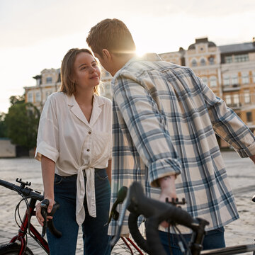 Young loving couple with bicycles kissing in city