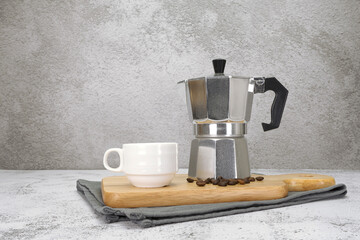 Coffee cup with moka pot and wooden tray on texture background.