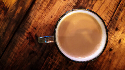 Coffee milk. A glass of hot milk coffee, on a wooden table background.