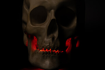 A skull with an illuminated jaw in red light. An ominous look that inspires fear