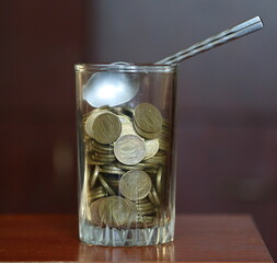 A glass glass with coins and a teaspoon