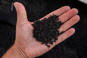 Recycled rubber in hand. Rubber crumb obtained in the process of recycling used car tires used for flooring sports and playgrounds. - obrazy, fototapety, plakaty