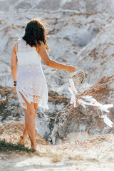 Beautiful girl in white dress holding a dreamcatcher in her hands.