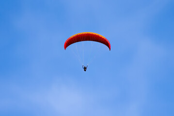 Paragliding in flight. Red and orange paraglider.