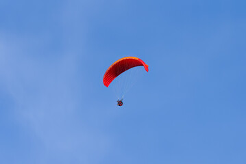 Paragliding in flight. Red and orange paraglider.