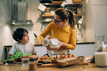 mother and son preparing pancakes together in home kitchen
