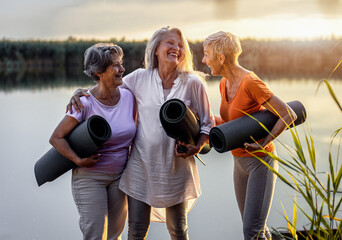 Group of senior woman with yoga mats talking after exercise.