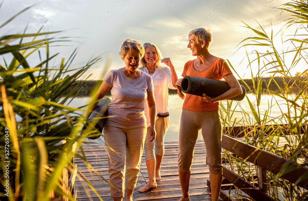 Wall mural Group of senior woman with yoga mats talking after exercise.