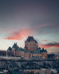 Fototapeta premium Vertical breathtaking view of old castle on pink sunset sky background in Quebec City