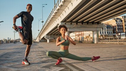 Black sports couple stretch on blurred city area