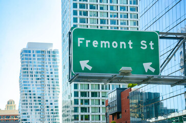 A large, green street sign for Fremont Street hanging from a modern glass office block in San Francisco, California, USA