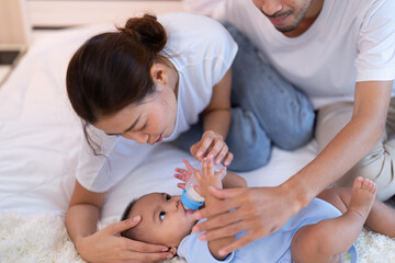Young Mom and father laughing joyful proud teasing playing kiss cheek and feet arm hold asian...
