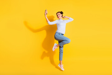 Fototapeta na wymiar Full length photo of sweet cute girl dressed white shirt recording video jumping high isolated yellow color background