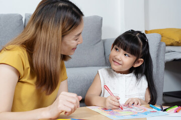 Asian girl smile with her mother and painting on paper with candle color.