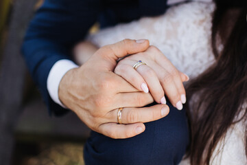 Couple holding hands. Bride and groom wedding photoshoot. Wedding ring and engagement ring on...