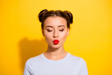 Portrait of adorable female kissing her boyfriend with close eyes isolated on yellow color background