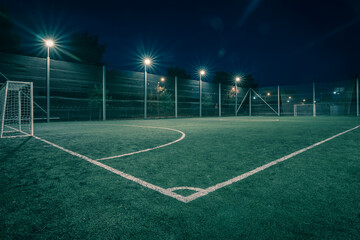 Plakat An amateur soccer field illuminated at night. A small football field lit by lanterns in the evening. Green football field illuminated at night. Soccer field in night with spotlight