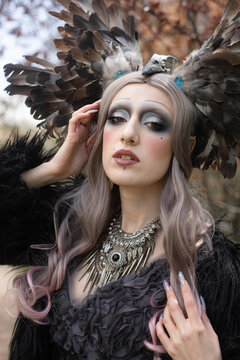 Portrait of a girl with fantasy makeup in the image of a witch with a crown of wings on her head
