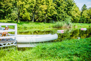 White pleasure boats at the pier on a small river in the city park. Summer day. A cluster of...