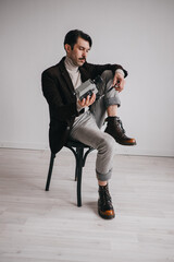 a young man in jeans and a jacket poses against a white wall in the studio.