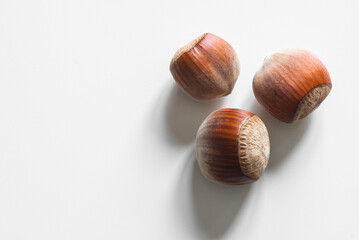 Three unopened hazelnuts against white background
