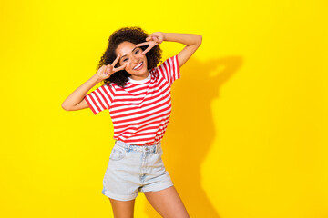 Portrait of young attractive pretty woman showing v-sign hello world friendly isolated on yellow color background