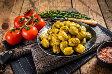 Barbecued organic olives with herbs in plate. Wooden background. Top view