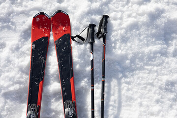 Mountain skis, sunscreen mask and ski sticks on bright alpine snow. Winter holidays. Extreme sport. Vacation, travel content. Copy space