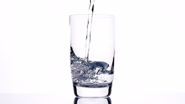 Fresh clean drink water in glass, Pouring pure drinking water into clear glass, splash out isolated on white background, slow motion. Concept of Drink Water, Flow, Healthy, Life, Nature, Transparent