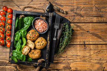 Seafood Fish balls or Fish cake with spinach and herbs in a tray. Wooden background. Top view. Copy...