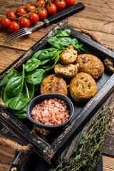 Seafood Fish balls or Fish cake with spinach and herbs in a tray. Wooden background. Top view