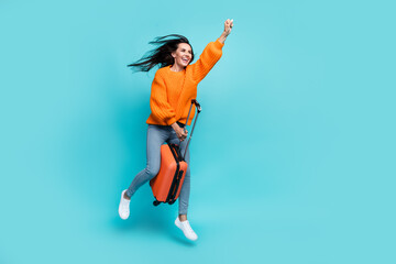 Fototapeta na wymiar Full size portrait of excited cheerful girl jump hold suitcase raise fist empty space isolated on turquoise color background