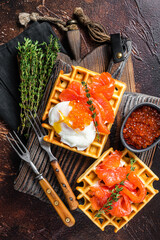 Waffle Sandwich with cream cheese, smoked salmon, egg and red caviar. Dark background. Top view