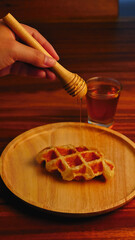 Freshly baked homemade waffles with honey on the table.
