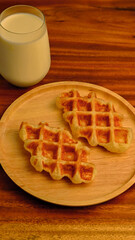 Freshly baked homemade waffle with milk on the table.
