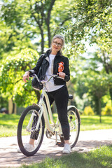 Fototapeta na wymiar Mature woman on a bike in a summer park