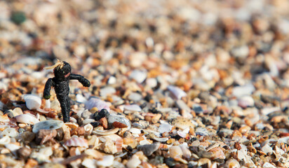 Toy men on the beach with colorful stones and shells, concept