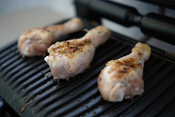 Cooking chicken legs on an electric grill, on the balcony of the apartment