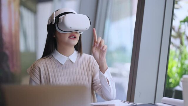 smart attractive asian female business owner weared virtual reality glasses enjoys casual metaverse meeting with concentrate at cafe restaurant,asian female  using headset in cafe