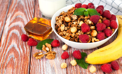 Crispy granola, ripe berries, banana and honey on the wooden table. Healthy breakfast in the morning. Сlose-up. Copy space.