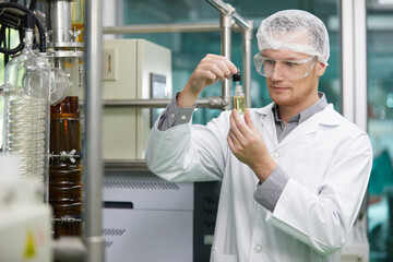 scientist testing and holding cannabis cbd oil bottle in chemical laboratory