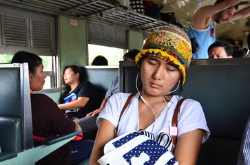 Thai women travelers people sit listen music and sleep dream on locomotive train after travel visit...
