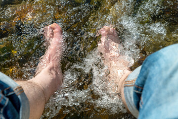 Flowing water between stones laps a man's feet in the sunshine
