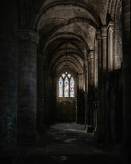 Interior of an ancient stone cathedral with pillars, arches, and large windows in Scotland, UK